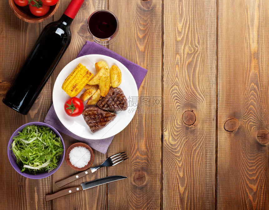 牛排配烤土豆玉米沙拉和红酒在木桌上带复制图片