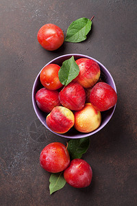 新鲜成熟的桃子在石头桌上的碗图片
