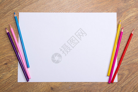 木桌背景上的彩色绘图铅笔和白纸图片