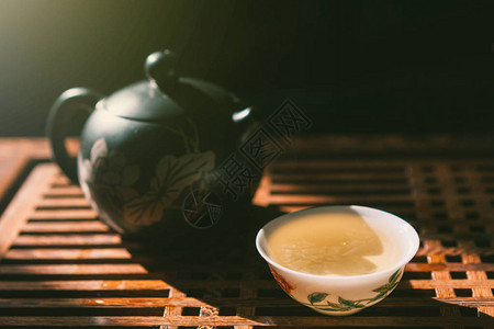 茶仪式茶壶和木制桌上的一杯绿色黄茶背景图片