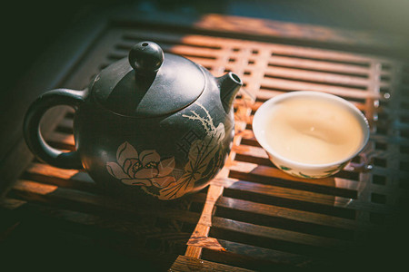 茶仪式茶壶和木制桌上的一杯绿色黄茶背景图片