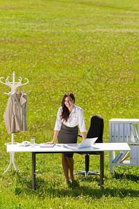 在阳光明媚的草地办公室的年轻女商人图片