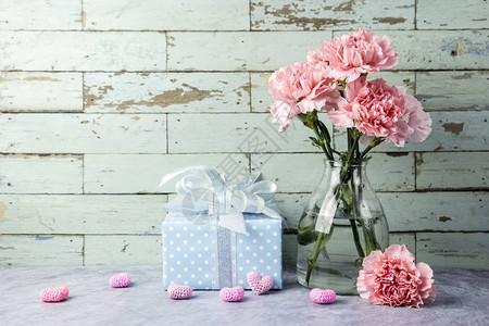 粉红康乃馨花在清晰的瓶子礼物盒和图片