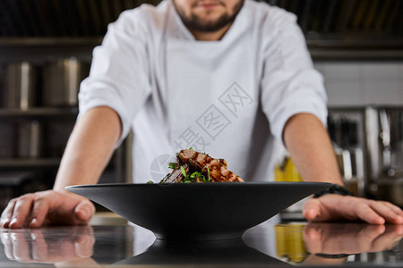 厨师在餐厅厨房的餐盘旁站着半边天花图片