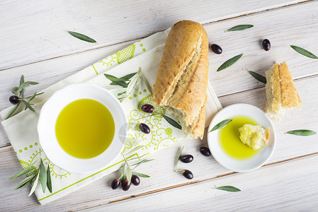 特级初榨橄榄油和白色木桌上的面包背景图片