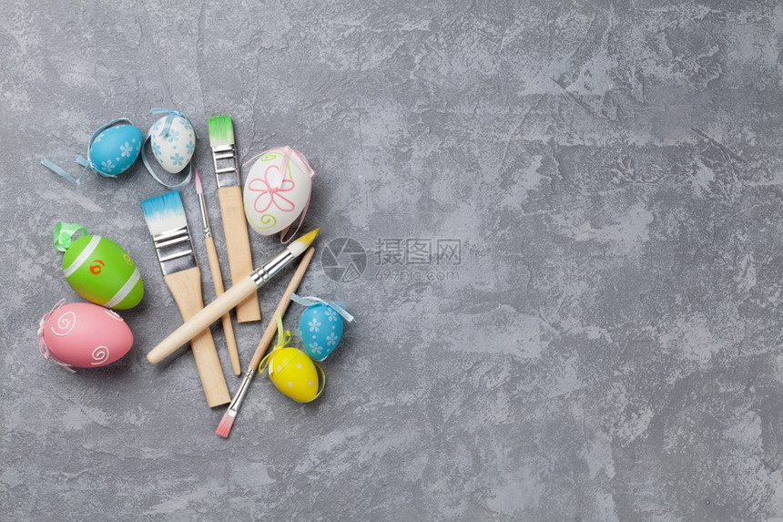 石头桌上有多彩的东边鸡蛋和绘画刷带有复制空图片