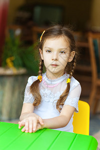 小女孩坐在绿色孩子的桌子上思考图片
