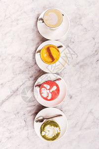 四种不同的彩色拿铁咖啡泡沫艺术风格现代咖啡馆白色大理石背景的天图片
