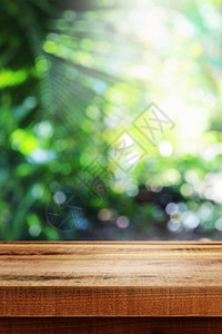 模糊的抽象绿色散景和木桌背景图片