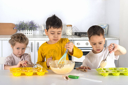 小女孩和两个男孩在屋子厨房做蛋糕图片