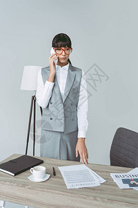 商业女商人在工作空间用智能手机说话孤图片