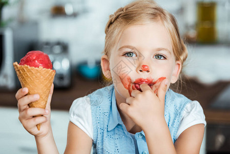 可爱的小孩一边舔手指一边吃甜冰淇图片