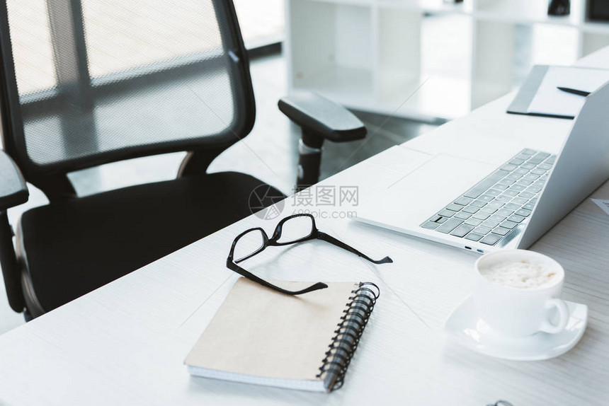 仔细观察办公室桌上的眼镜笔记本咖啡杯图片