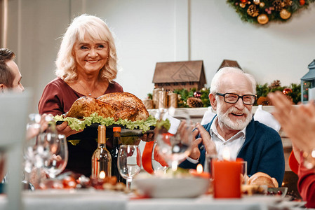 在圣诞节桌的老年夫妇与美味的图片