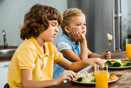 不快乐的小孩吃蔬菜的侧视图图片