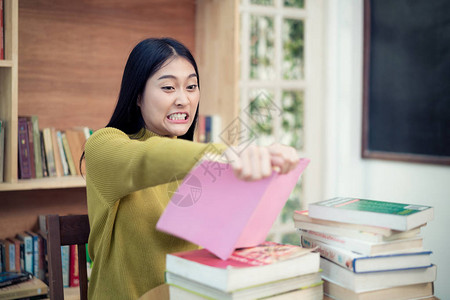 愤怒的亚洲女大学生在读不懂的书时撕裂她图片
