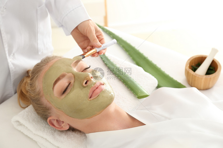 美容师在美容院对年轻女子的脸部使用面罩蒙上aloevera图片