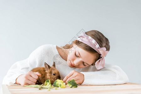 可爱的可爱女孩在木桌上用西兰花喂养图片