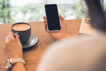 咖啡厅餐桌上使用智能手机的咖啡杯妇女图片