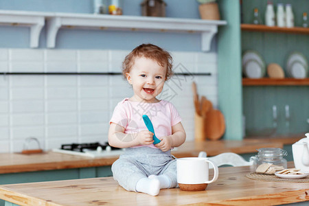 快乐的婴儿坐在厨房的桌子上图片