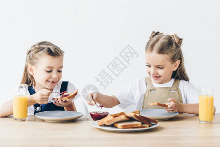 笑着的小姐妹们在吃东西吃果酱加烤面包做早餐图片