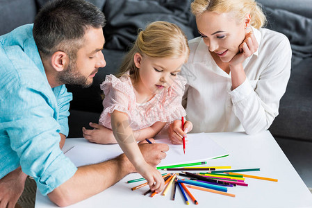 家庭的一个孩子在家里用彩色铅笔一起绘画图片