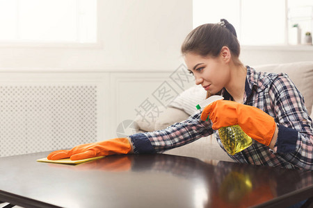 在木质表面使用喷雾清洁剂的妇女微笑的女孩打扫家具家务和家务劳动概图片