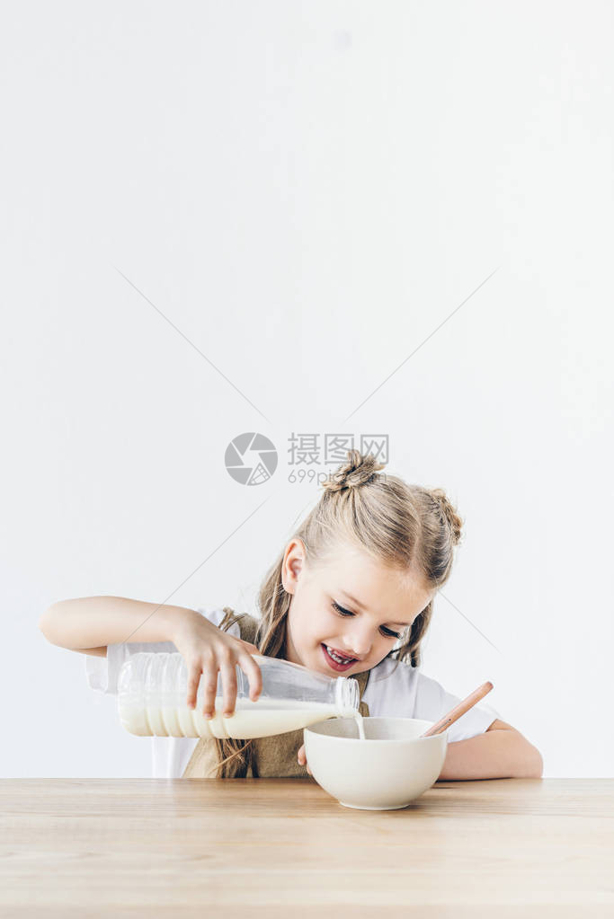 带着微笑的小女学生将牛奶倒进麦片图片