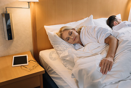 睡在床上的浴袍和数字平板上面眼镜放在旅馆房间桌图片