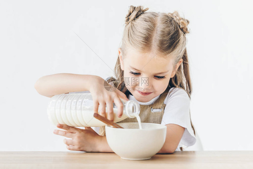 快乐的小女学生将奶水倒进麦片图片