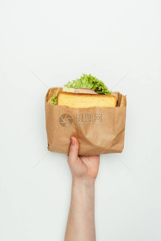 妇女将三明治放在纸袋中孤立在白色上的妇图片
