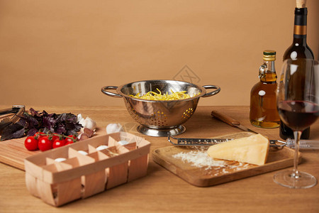 面条和木制桌上的红酒环绕着意大利面粉图片