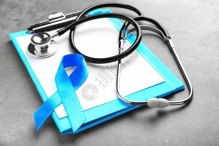 灰色背景上的蓝丝带听诊器和剪贴板前列腺癌概念图片