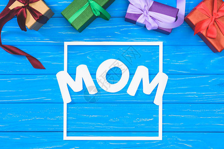 礼物盒和蓝桌框中的妈字词母亲日概背景图片