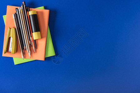 蓝色背景的教科书不同铅笔订书机和胶图片