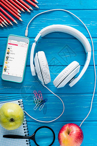 屏幕耳机苹果和蓝木背景文具上的苹果音乐应用软件的智能图片