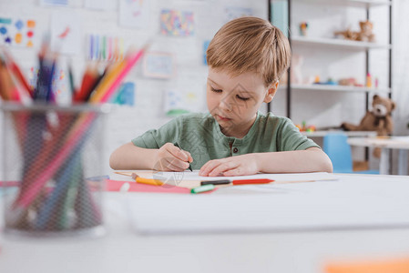 学龄前儿童在教室桌子上用铅笔画的肖像背景图片