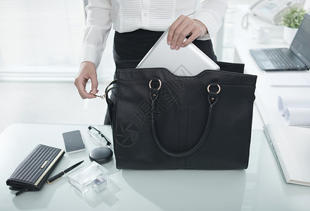 商业女商人把基本的东西放进她的手提包从图片