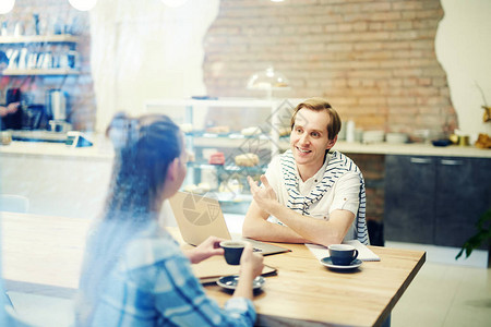 微笑的男人在咖啡店与妇女面谈图片