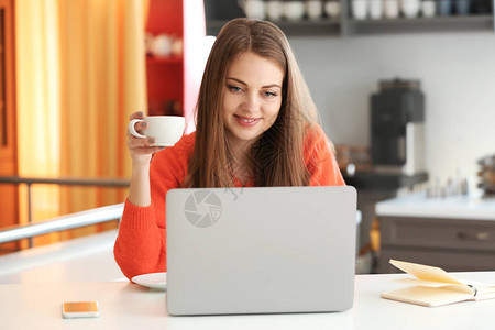 在家用笔记本电脑工作时喝咖啡的女图片