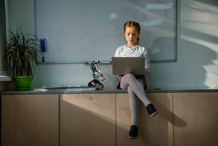 小女孩在课堂上用笔记本电脑与diy机器人图片