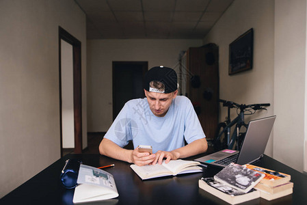 一名年轻学生在学习时使用电话在家教学十几岁的男孩在他的房间图片