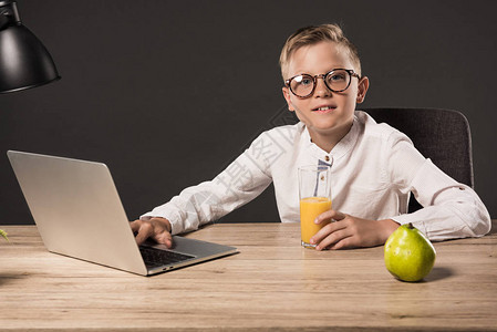 使用笔记本电脑在桌边用灯果汁杯和灰色底面的梨子制作的小男图片