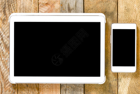 白色平板电脑和智能手机木桌上的手图片