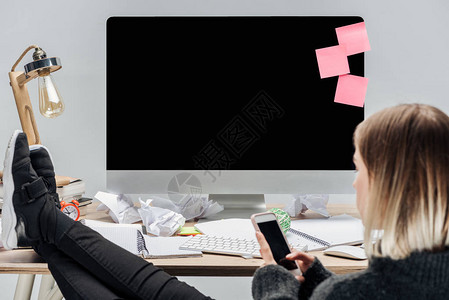 女孩有选择地集中关注坐在乱的工作场所并使用在灰色上隔离的智图片