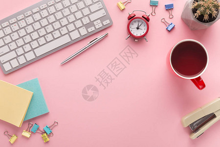 有咖啡杯键盘闹钟和粉红色背景的文具复制空间顶视窗的办公桌图片