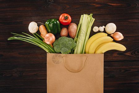 木制餐桌购物袋中不同蔬菜和水果的首观图片
