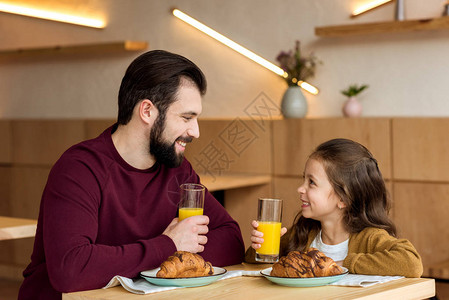 快乐的父亲和女儿拿着杯子橙汁看图片