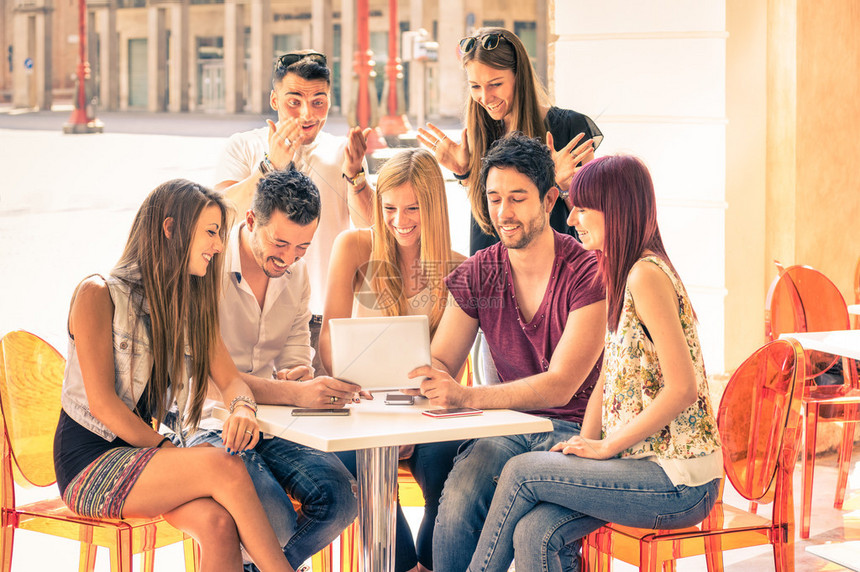 朋友组坐在餐厅酒吧玩平板电脑年轻学生在市中心使用便携式计算机连接的人社区在框架中间聚焦图片