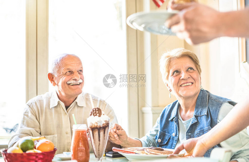 服务员在时尚生物餐厅为老年退休夫妇吃蛋糕养老金和活跃的老年人概念与成熟的人一起享受真正的乐趣以女为重点图片